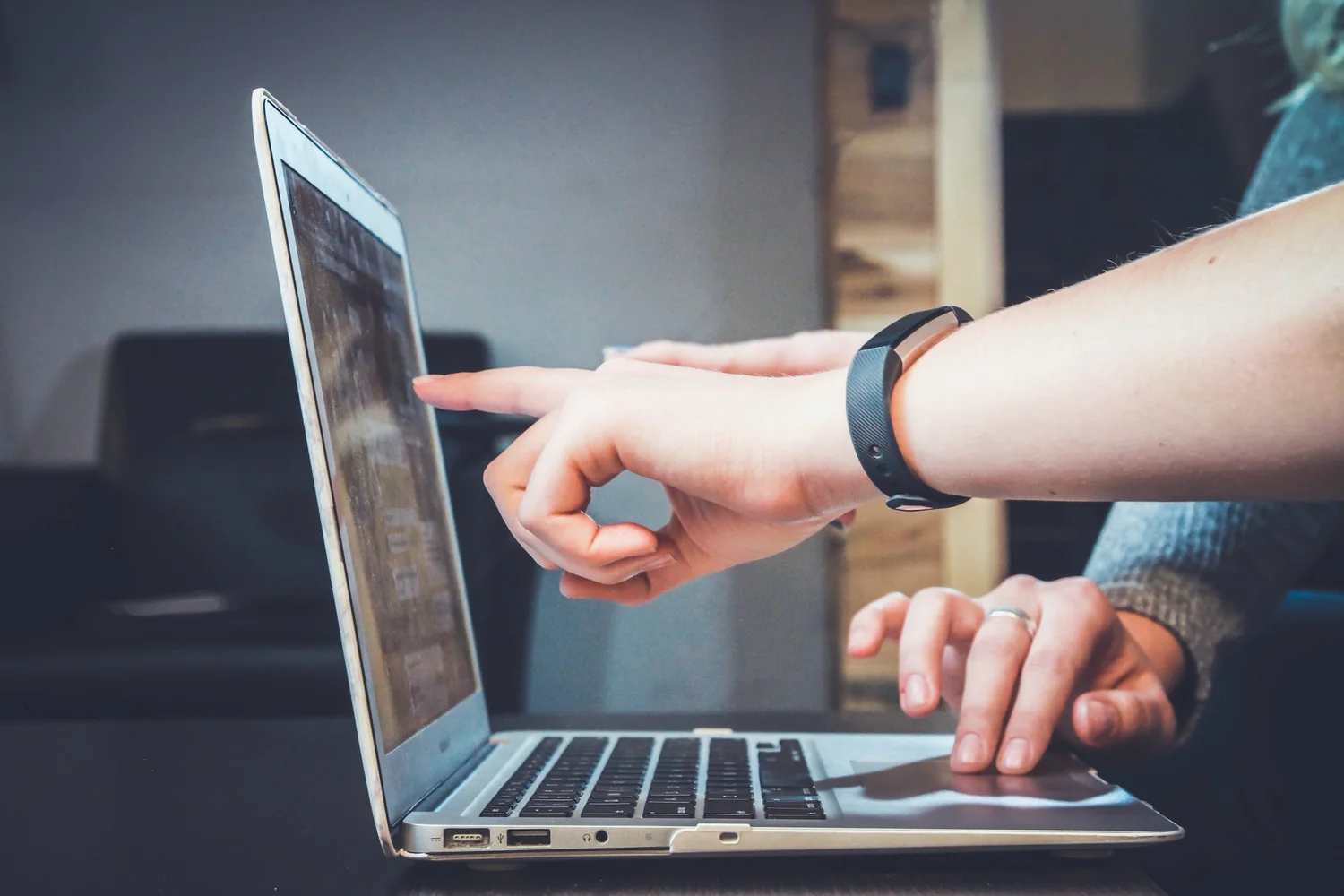 Hands pointing at and working on a laptop